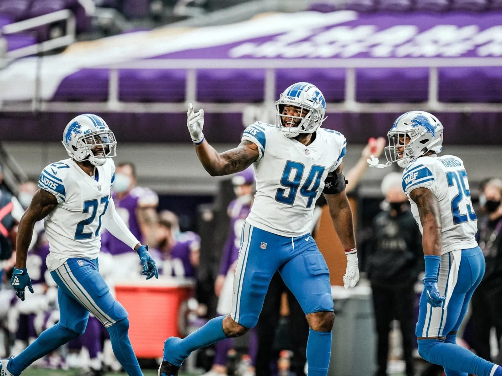 Austin Bryant celebrating with Detroit Lions teammates on the field