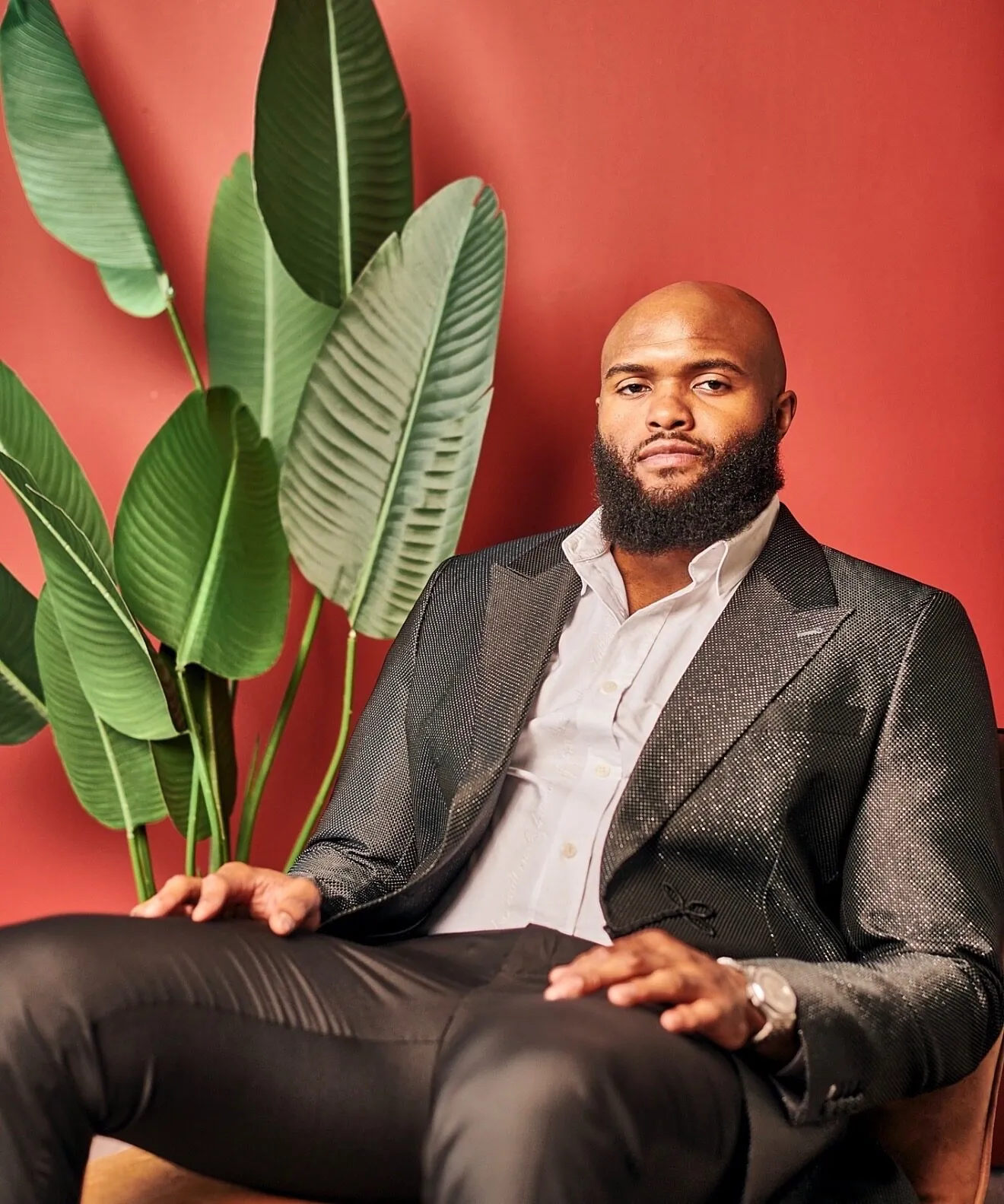 Austin Bryant seated in a dark suit against a red wall